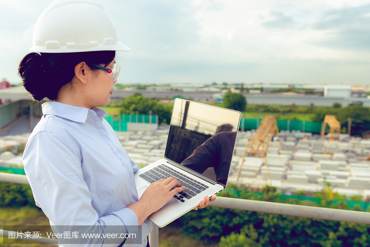 女工程师正在用笔记本电脑检查工厂里的预制混凝土产品